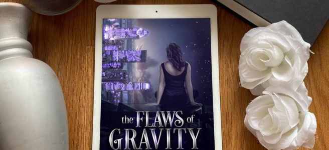 The Flaws of Gravity book surrounded by a silver column, white roses, and a blue candle