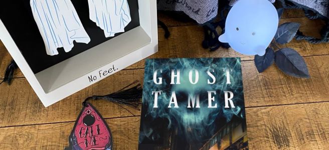 Ghost Tamer book on a wooden backdrop with a little ghost light and a wooden ghost decorative figure